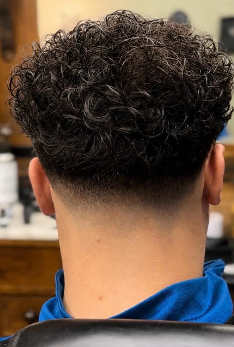 Krullend kapsel met strakke low fade bij Barbershop De Maten in Apeldoorn